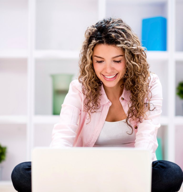 Smilende dame som jobber på en laptop